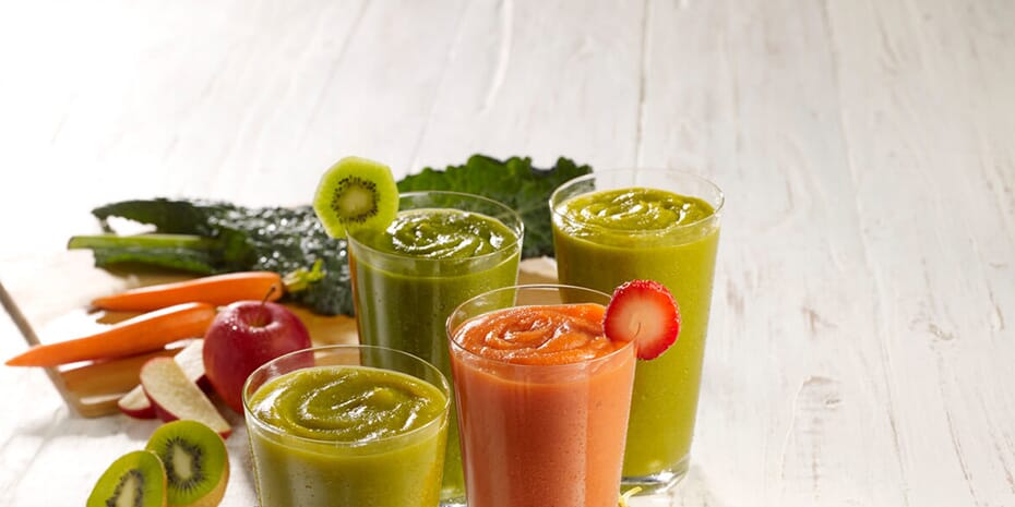 A group of convenient and nutritious smoothies with fruits and vegetables on a wooden table.