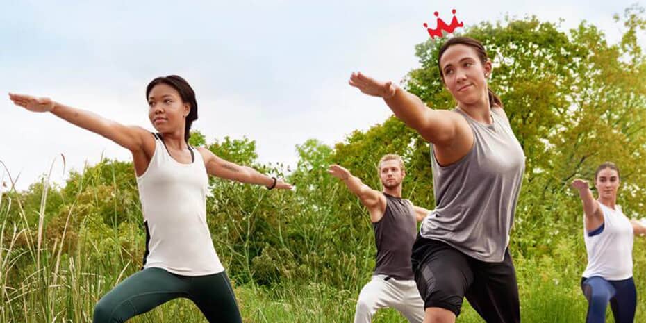 A group of people challenging their guests to rule the day by doing yoga in a field.