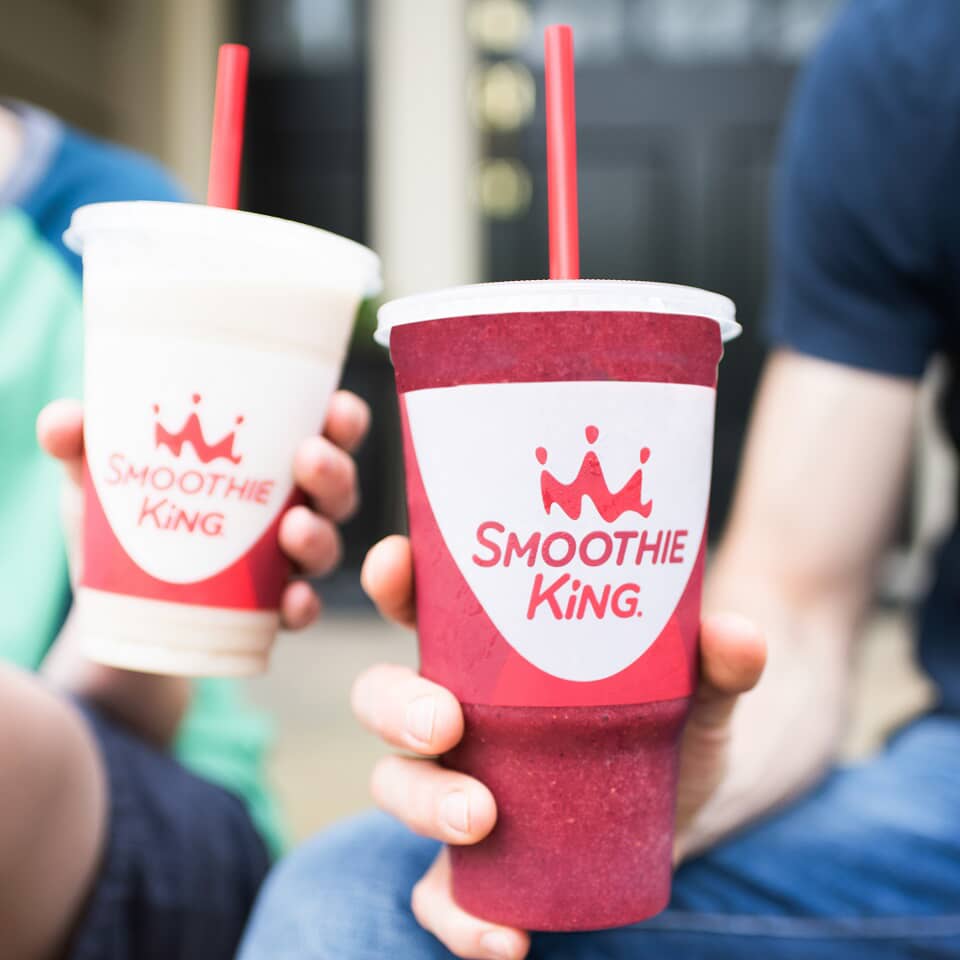 Two franchisees demonstrating successful changes in their system while holding Smoothie King cups.