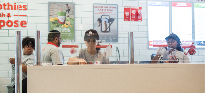 A group of people standing at a counter in a store while seeking exceptional restaurant franchise staff.