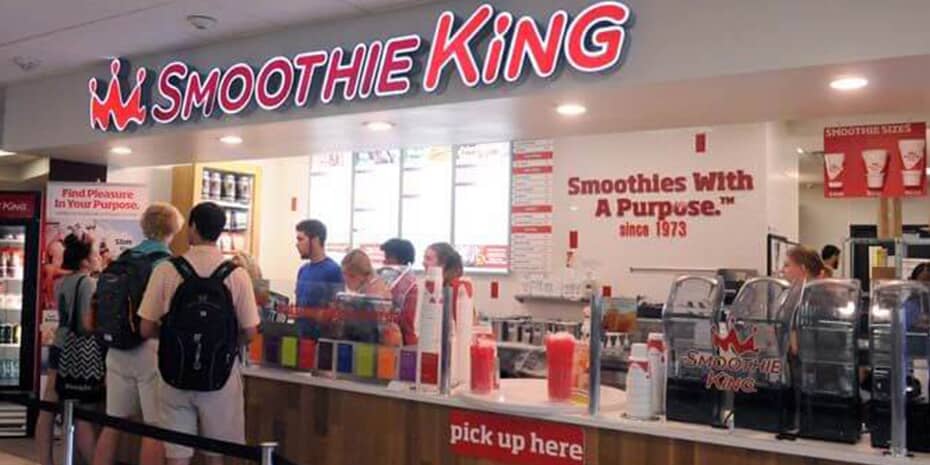 A group of people standing in front of a Smoothie King franchise.
