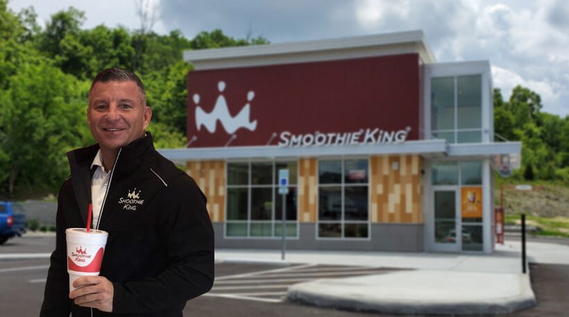 A man holding a cup of Smoothie King at the crossroads.