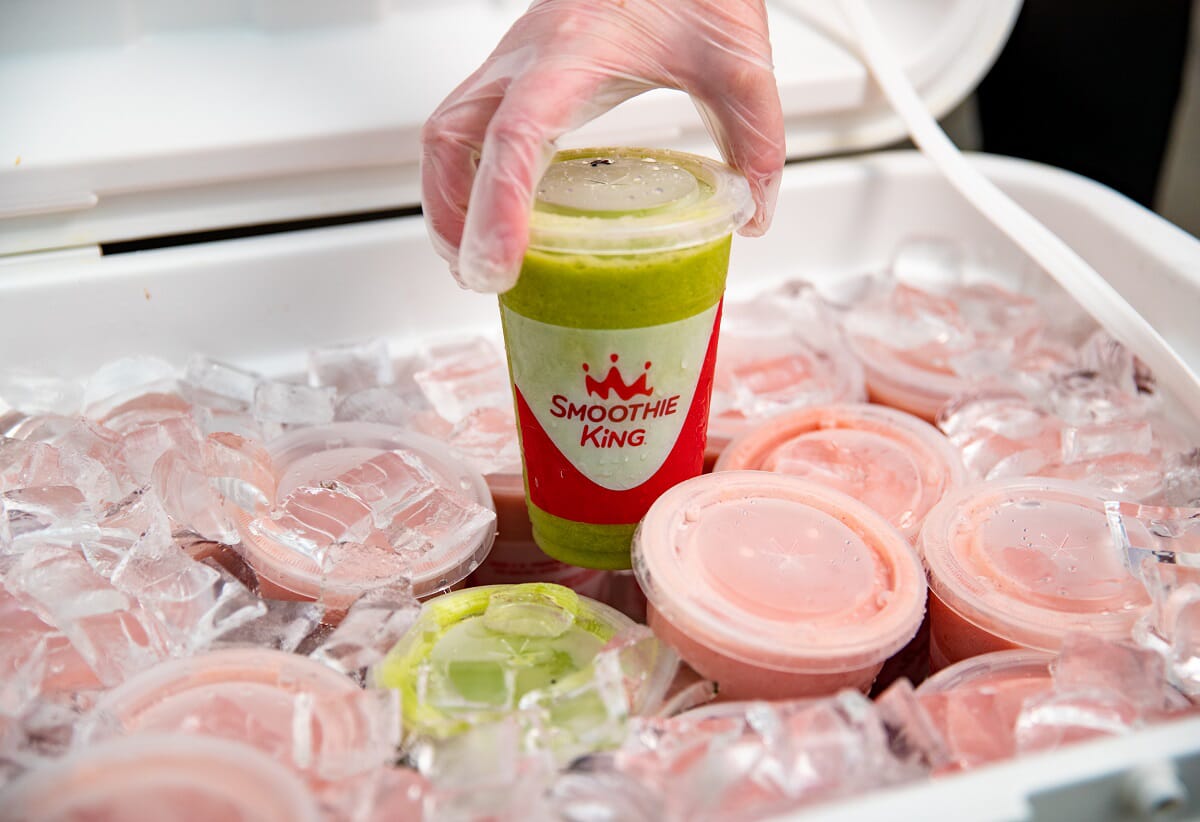 A person is pouring a smoothie into a cooler that showcases The Smoothie King Difference.