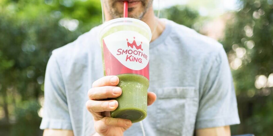 A man is holding a green smoothie in his hand, questioning if he's harnessing enough guest feedback.