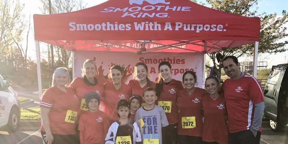 A group of guests fueling our growth pose under a tent at a race.