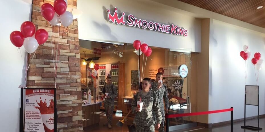 Two Navy veterans standing in front of a store with balloons, fulfilling the demand for smoothies on military bases.