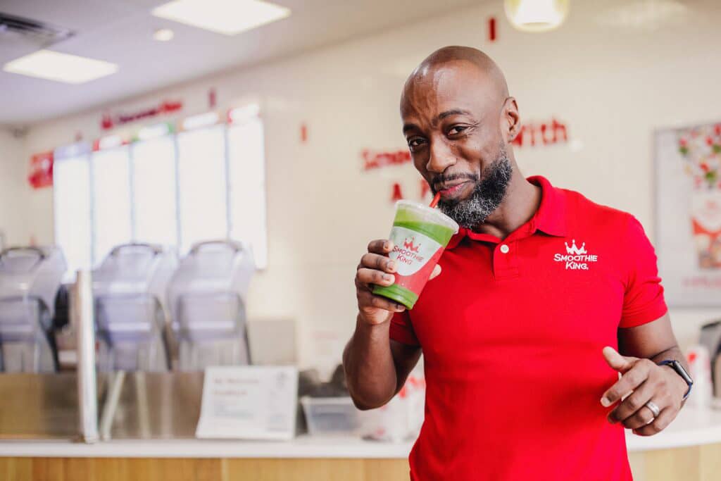 A man in a red shirt enjoying a smoothie.