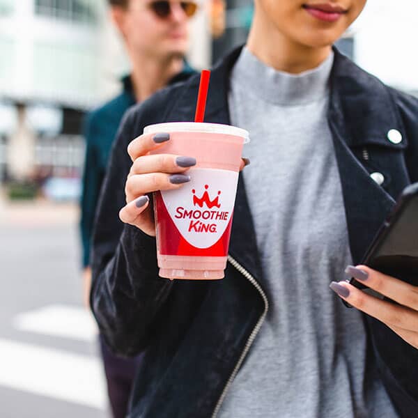 A woman enjoying a milkshake on the street.