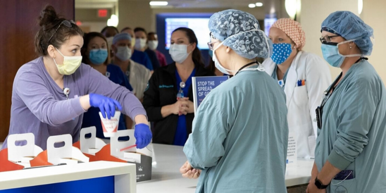 A group of people wearing masks and gloves at a hospital receives a generous smoothie donation from Smoothie King.