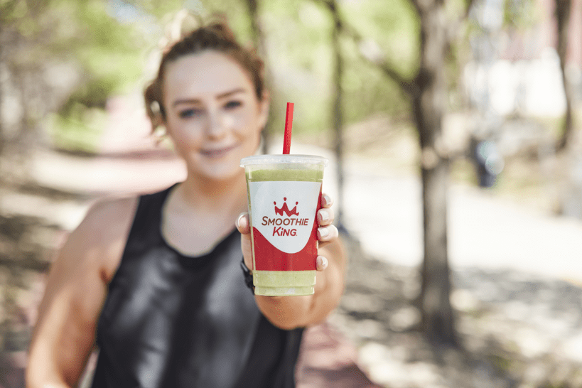 A woman showcasing a green smoothie, emphasizing its relevance to gut health and the current trend.