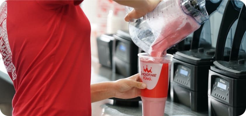 smoothie king employee pouring a pink smoothie