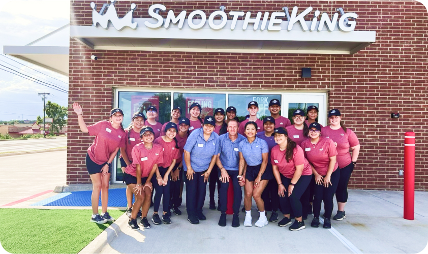 Staff of a smoothie king store posing for a picture at the front of the store